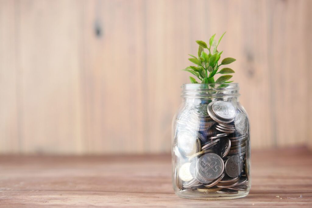 Potes de vidro com moedas e mudas de planta representando a reserva de emergência